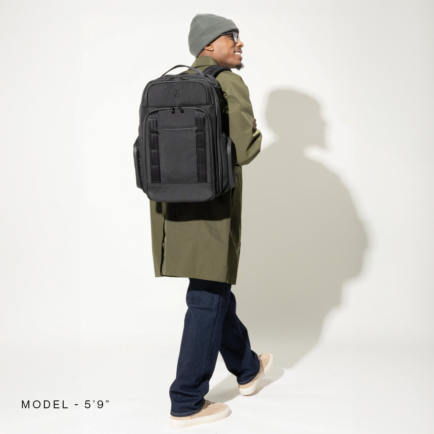 Person wearing a large black backpack on a plain background