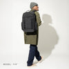 Person wearing a large black backpack on a plain background