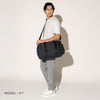 Person wearing a aviator navy duffel over the shoulder on a white background