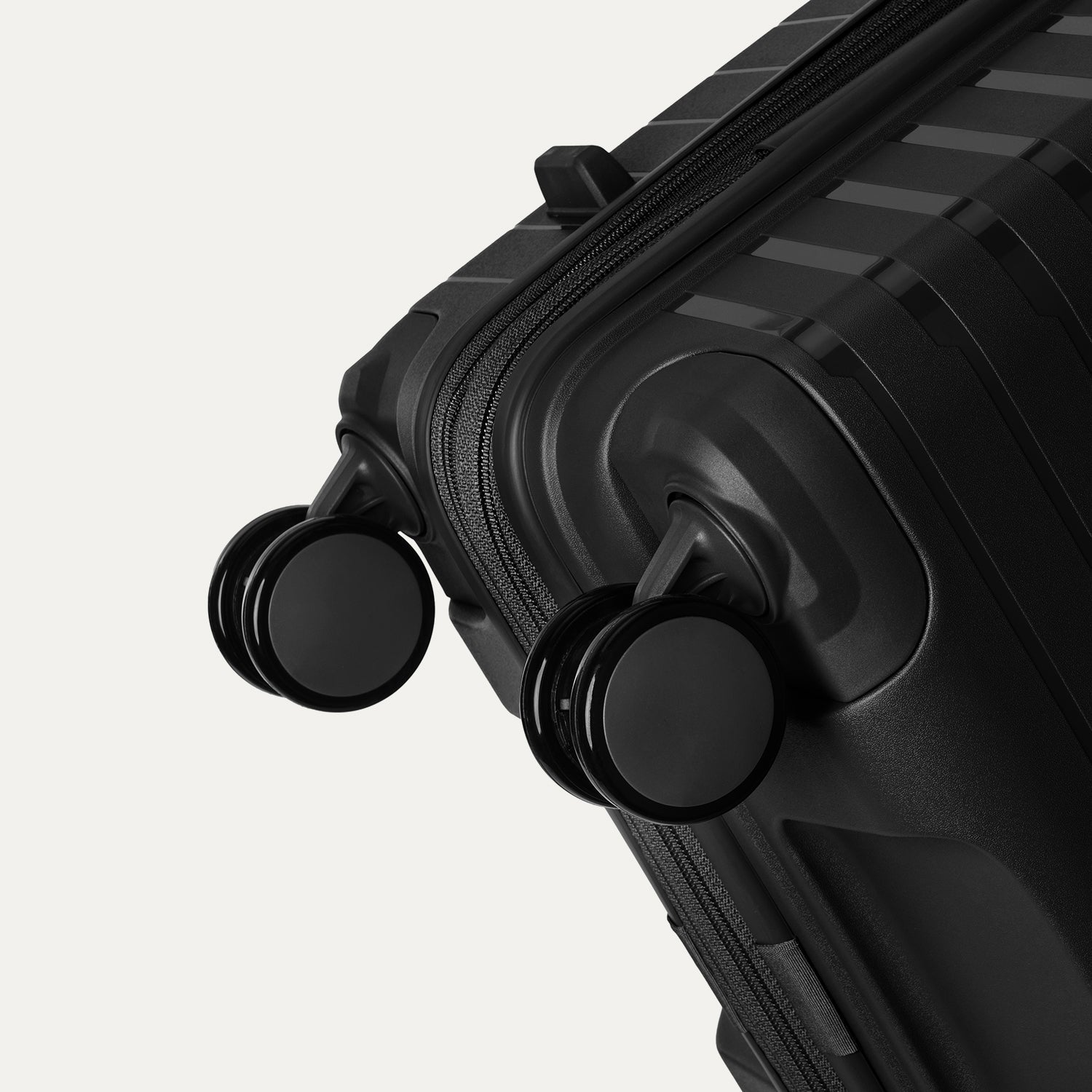 Close-up detail view of the Optima Expandable Medium Check-in Spinner in Black, showcasing the self-aligning spinner wheels and the reinforced corner construction.
